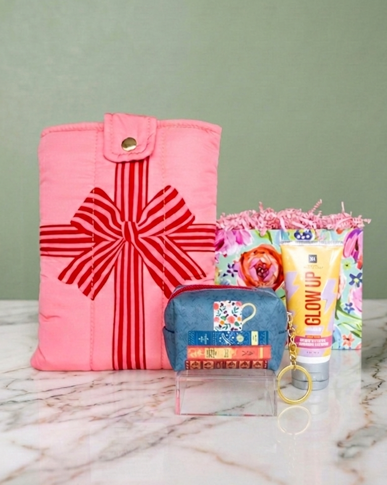book reader accessories gift set includes pink book/e-reader cover with red bow, small blue with a stack of book designed keychain pouch, and infused sea-salt hand cream.
