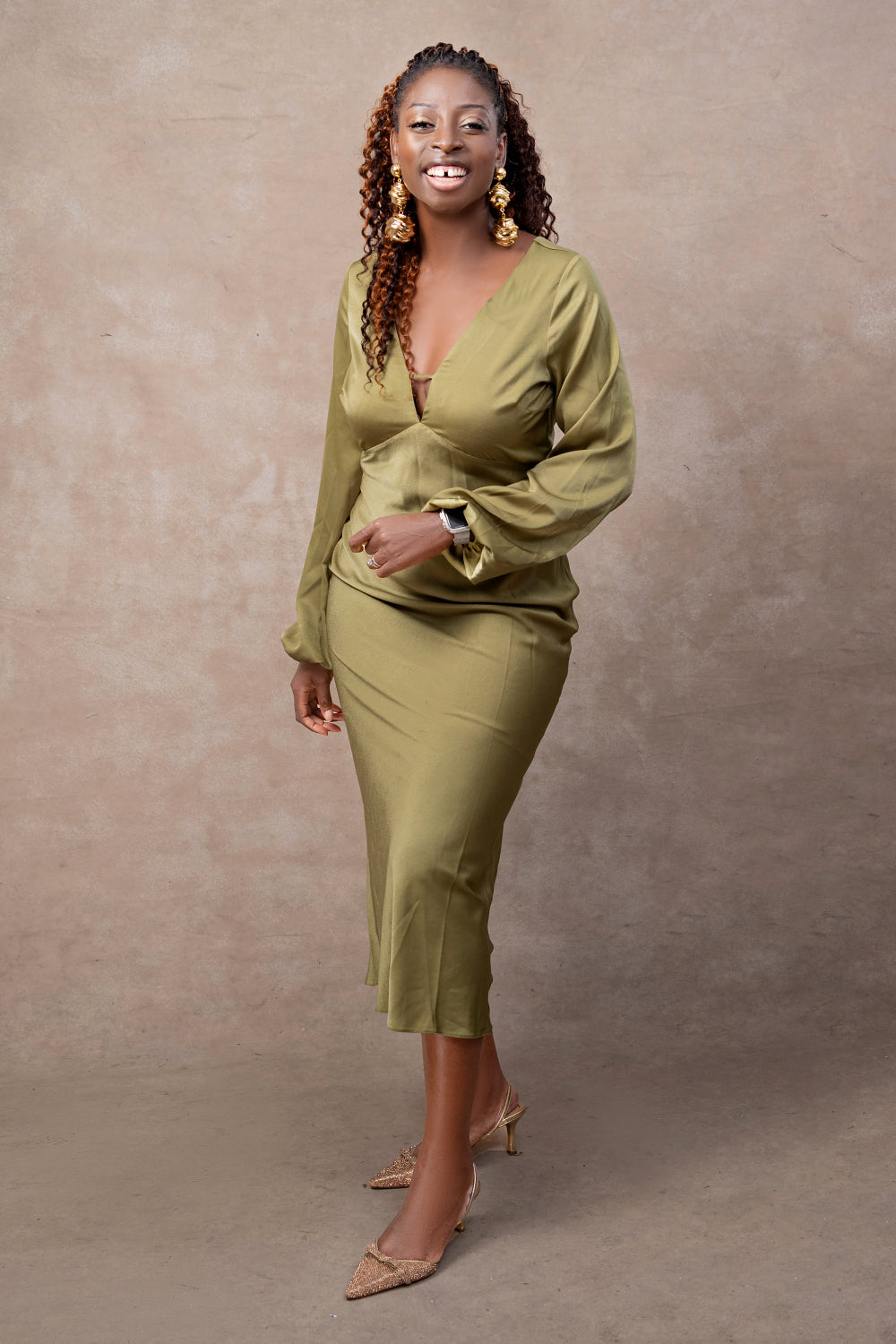 A woman who is a gifting experience designer, wearing a green outfit against a beige background. She is the founder of Didun & Co, a gifting brand specialize in beautifully packaged, elevated gifts for special occasions and corporate gifting.