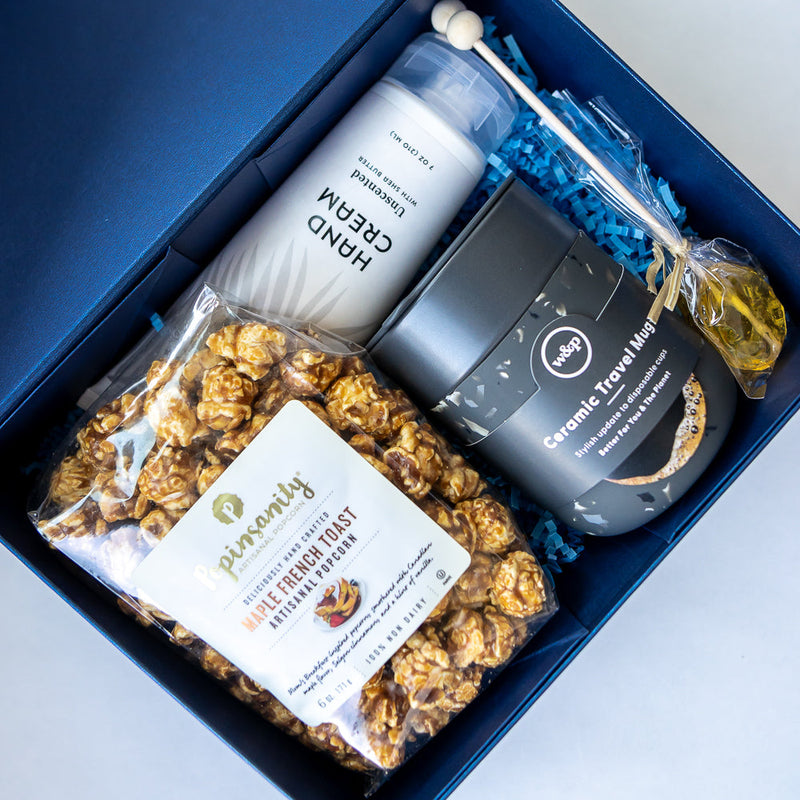 Gift box containing popcorn, hand cream, and other items on a white background