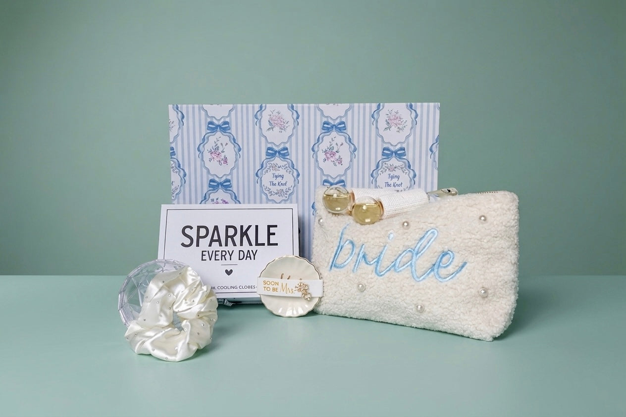 Mrs. Glam bridal gift set with pearl pouch, embroidered with 'bride' in blue and ring dish with crystal earring studs for the "soon to be" Mrs, a white crystal beaded hair scrunchie in a clear crystal diamond case, and a  'SPARKLE EVERY DAY' box that includes a eye cooling globes. Upgraded keepsake gift box. 