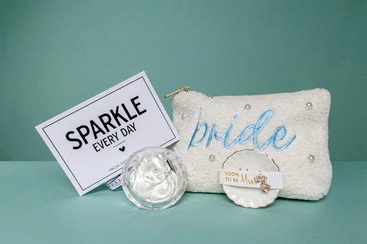 Mrs. Glam bridal gift set with pearl pouch, embroidered with 'bride' in blue and ring dish with crystal earring studs for the "soon to be" Mrs, a white crystal beaded hair scrunchie in a clear crystal diamond case, and a  'SPARKLE EVERY DAY' box that includes a eye cooling globes. 