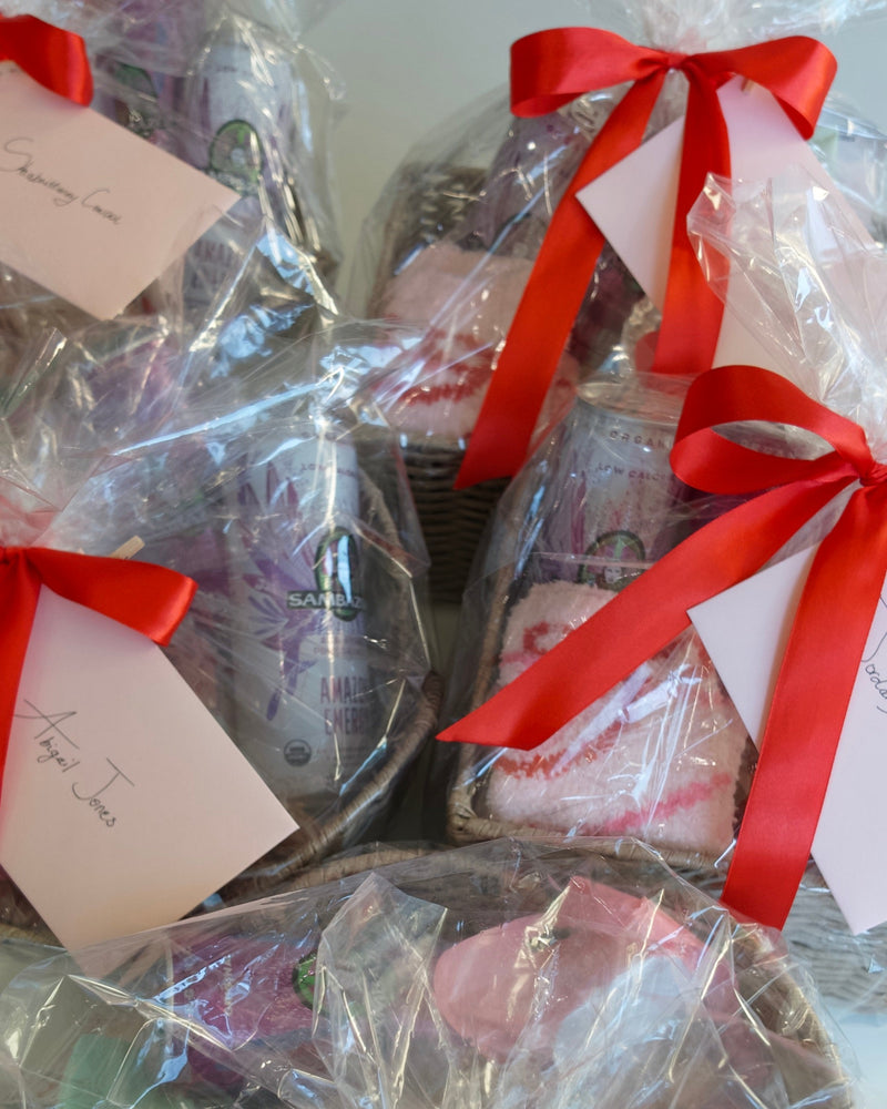 Several curated gift baskets for thank you nurses appreciation wrapped in clear cellophane with red ribbons and handwritten cards, arranged together
