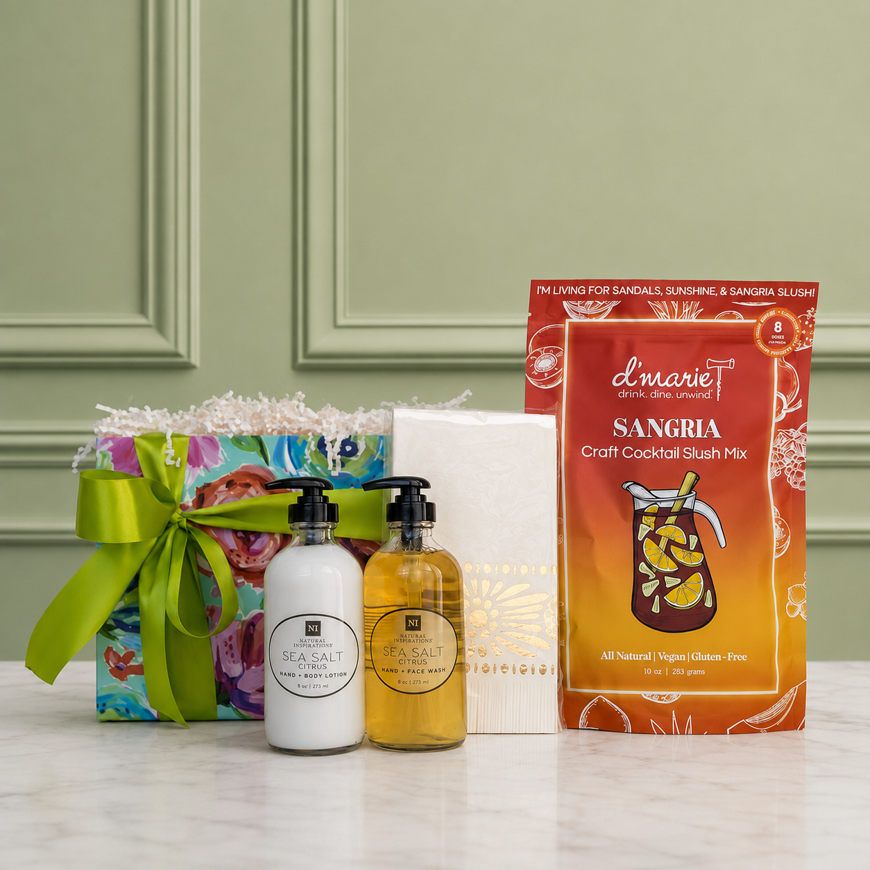 A housewarming curated gift collection including sea-salt citrus scented hand wash and lotion with bamboo tray, Moroccan pattern guest napkins and sangria cocktail slush mix. Beautifully arranged in a floral gift box with a satin ribbon.